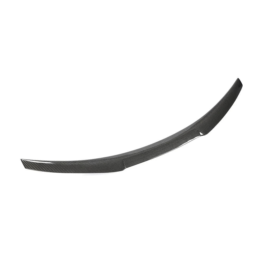 Curved carbon fiber car spoiler resting against a plain white background, showing a streamlined design with a textured surface that enhances aerodynamic performance.
