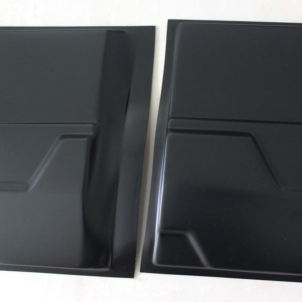 Two black metal panels lie side by side on a light surface, featuring subtle geometric indentations and smooth, reflective finishes, suggesting industrial or construction use.