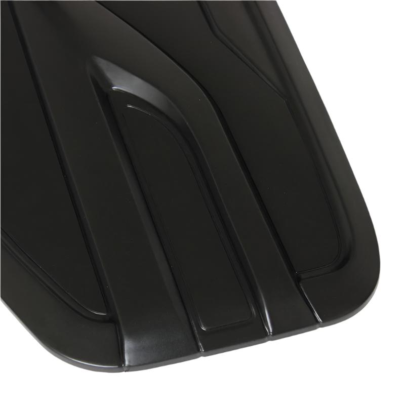 A black, sleek surface with raised, angular grooves creates a modern, aerodynamic design, possibly part of automotive equipment, shown in close-up detail, highlighting its stylish contours.