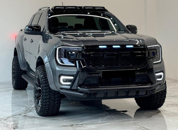 A sleek, black pickup truck with illuminated headlights and roof lights is parked indoors on a glossy tiled floor, emphasizing its rugged design.