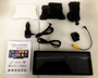 A collection of car accessories including a touchscreen, mounts, power adapter, and cables, arranged on a white foam surface. Includes manual: "Portable Car MP5 Player, Wireless CarPlay & Android Auto, Model: B5303", showing app icons.