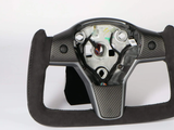 Steering wheel frame missing central cover, revealing internal mechanisms and wiring, features a carbon-fiber design and black suede grip, situated in a neutral studio setting. No text present.