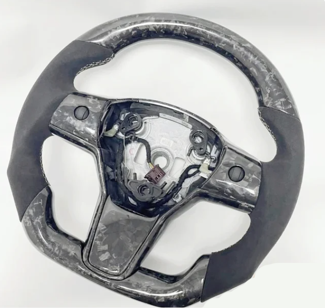Steering wheel without a center cover, exposing internal wiring and mechanisms, featuring a carbon-fiber pattern, situated on a plain white background.