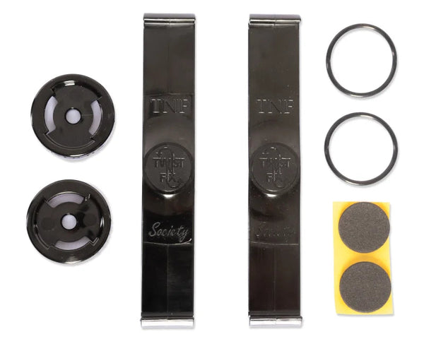 Metal clips labeled "TWF" and "Society" are placed centrally. Surrounding them are two black circular discs, two rubber rings, and a small yellow square with two round gray pads.