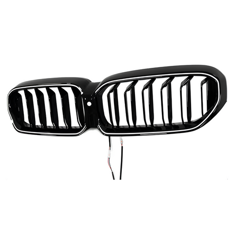 A shiny black car grille with vertical slats is suspended against a plain white background. Two wires dangle below, indicating electrical connectivity for installation.