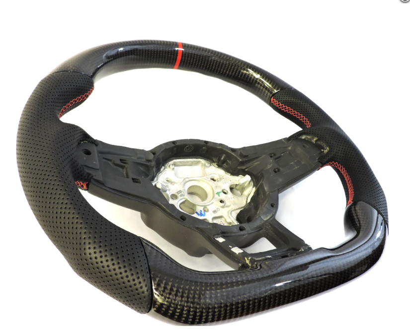 A black carbon fiber car steering wheel with perforated grips and red stitching sits on a white background, displaying its central mounting hub surrounded by intricate details.