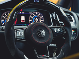Steering wheel with Volkswagen logo rests in a car's driver seat, surrounded by a modern digital dashboard showing a rev counter, speedometer, and car image. Display reads: 