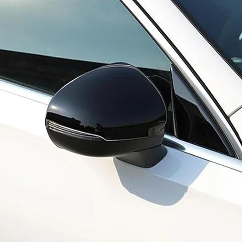 A black side mirror is attached to a white car, reflecting light in a sunny outdoor setting. The vehicle's window and frame are partially visible.