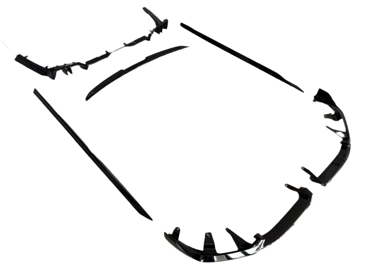 Black car body kit components lay spread apart on a white background, showing a front splitter, side skirts, and a rear diffuser for automobile customization.