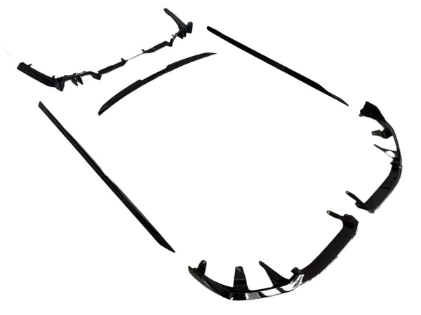 Black car body kit components lay spread apart on a white background, showing a front splitter, side skirts, and a rear diffuser for automobile customization.