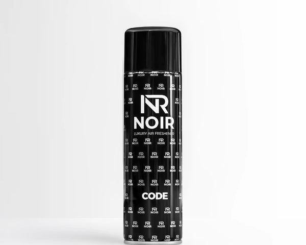 A black aerosol can stands on a smooth surface with a minimalist background. The can displays the text: "NR NOIR LUXURY AIR FRESHENER CODE" and is patterned with smaller "NR NOIR" logos.