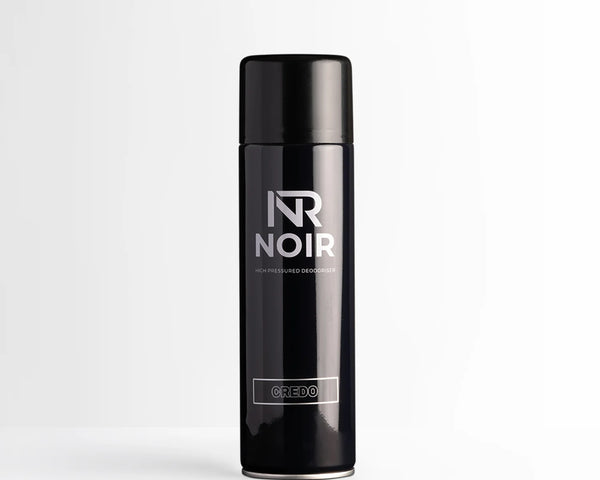 A black cylindrical deodorant can labeled "NR NOIR HIGH PRESSURED DEODORISER CREDO" stands upright, centered on a smooth white surface against a light gray background.
