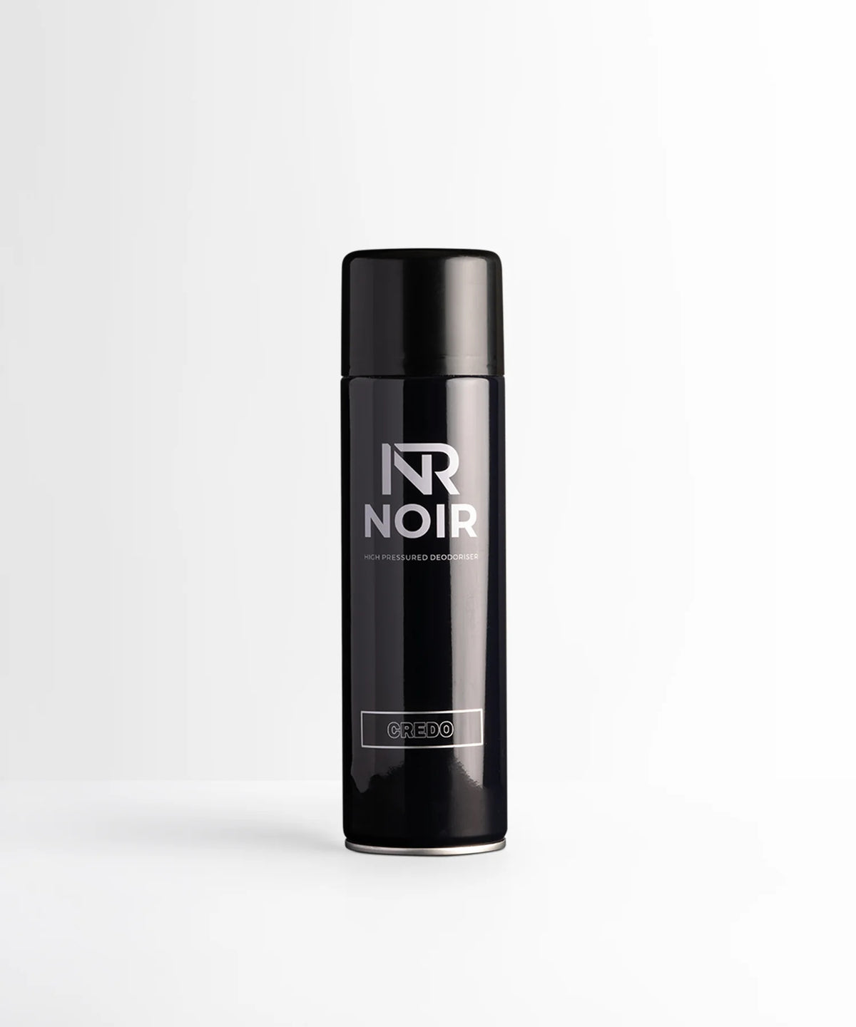 A black cylindrical deodorant can labeled "NR NOIR HIGH PRESSURED DEODORISER CREDO" stands upright, centered on a smooth white surface against a light gray background.