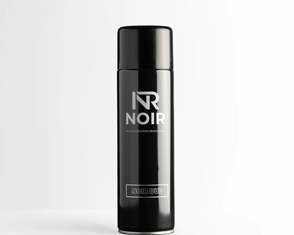 A black cylindrical deodorant can stands on a white surface. Text reads: "NR NOIR HIGH PRESSURED DEODORISER NOIR OUD." The background is a plain white wall.