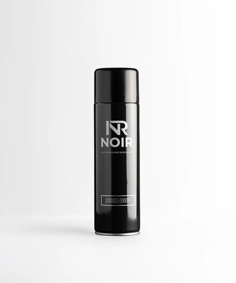 A black cylindrical deodorant can stands on a white surface. Text reads: "NR NOIR HIGH PRESSURED DEODORISER NOIR OUD." The background is a plain white wall.