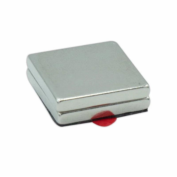 A square silver magnet presses against a flat surface, with a small red tab protruding. The background is plain white, emphasizing the magnet's metallic sheen and compact size.