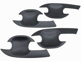 Four black, curved plastic door handle covers are arranged on a plain white background. Each cover features a cutout design, tailored to fit vehicle door handles.