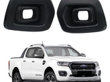 Two black plastic fog light covers are displayed above a white pickup truck with a modern design, parked on a plain white background.