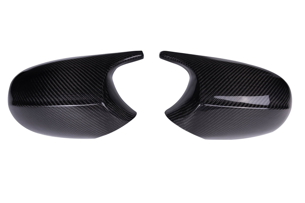 Two glossy carbon fiber mirror covers facing each other, exhibiting curved shapes and smooth surfaces, set against a plain white background.