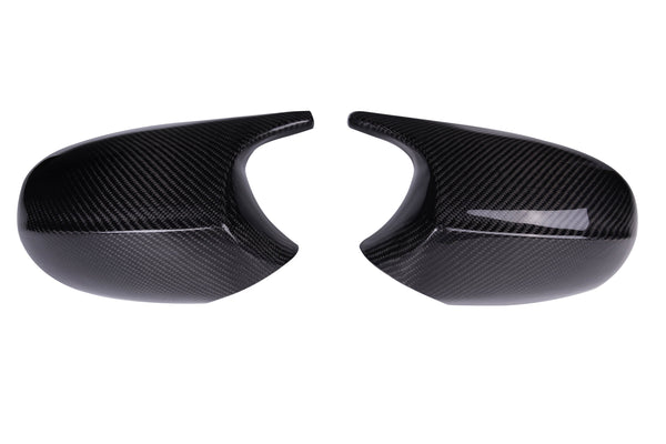 Two glossy carbon fiber mirror covers facing each other, exhibiting curved shapes and smooth surfaces, set against a plain white background.