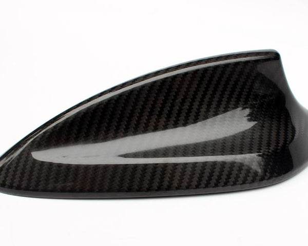 A carbon fiber car antenna cover with a sleek, aerodynamic design rests on a plain, white background.