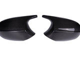 Two black carbon fiber car mirror covers are placed side by side on a plain white background, showcasing a glossy finish and a textured pattern.