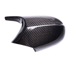 A black carbon fiber motorcycle mirror cover reflecting light, showcasing a glossy finish and textured pattern, isolated on a white background.