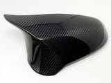 A glossy carbon fiber car mirror cap with a sleek, curved design, rests on a plain white background, showing its textured surface.