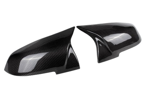 Two carbon fiber car mirror caps are displayed side by side on a plain white background, showcasing their glossy, textured finish and sleek aerodynamic design.