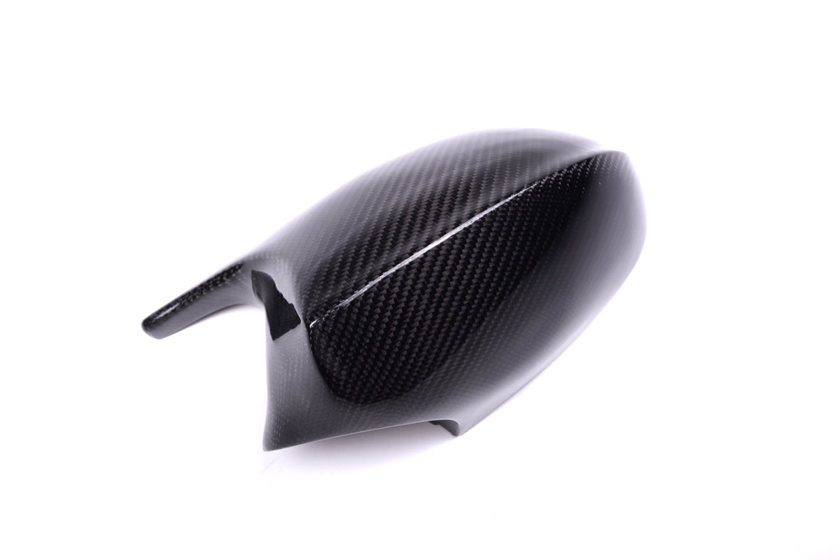 Carbon fiber car mirror cover, resting stationary, on a plain white background. The cover reflects light with a subtle pattern, indicating its sleek and lightweight design.