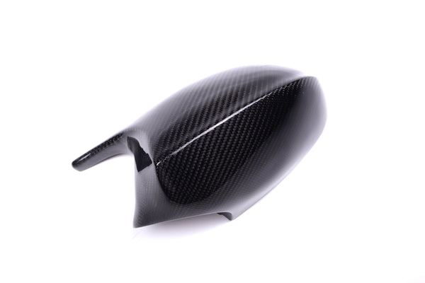 A sleek, black carbon fiber side mirror cover sits on a white background, displaying its glossy finish and textured pattern, suggesting automotive use.