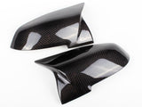 Two glossy carbon fiber car mirror covers are displayed on a white background, showcasing their sleek, aerodynamic design and checkered pattern.