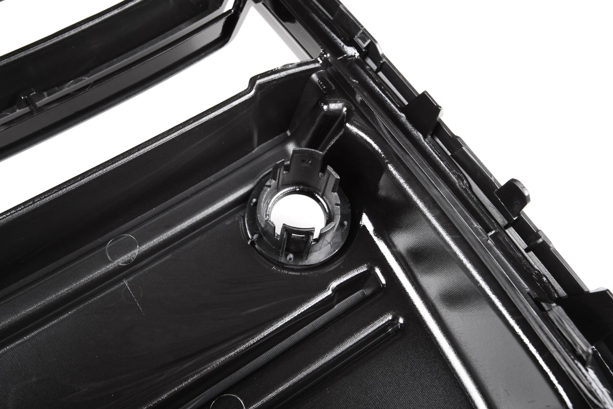 A glossy black plastic automotive part with a circular mount and ridges is shown in close-up, likely part of a larger engine or mechanical assembly.