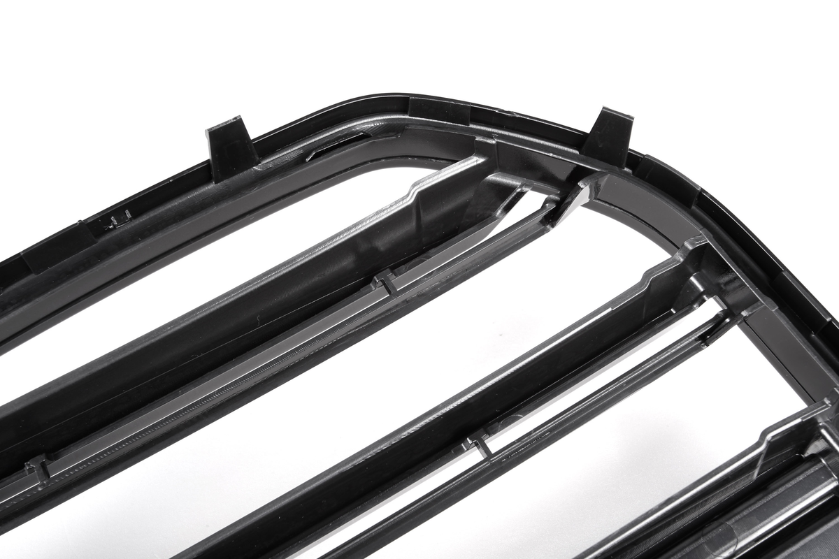 A black plastic car grille with horizontal slats, positioned diagonally, on a plain white background, highlighting the structure and texture of the material.