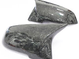 Two carbon fiber side mirror covers rest on a white background, showcasing a sleek, glossy finish with a textured pattern.