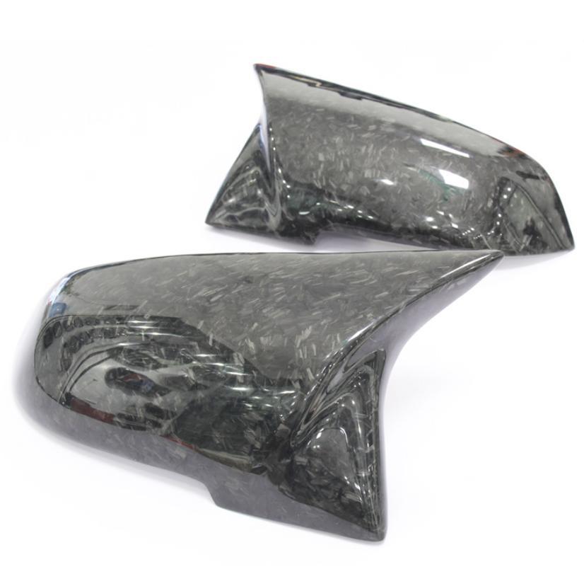 Two carbon fiber side mirror covers rest on a white background, showcasing a sleek, glossy finish with a textured pattern.