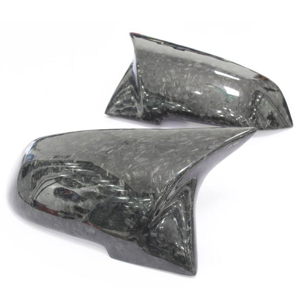 Two carbon fiber side mirror covers rest on a white background, showcasing a sleek, glossy finish with a textured pattern.