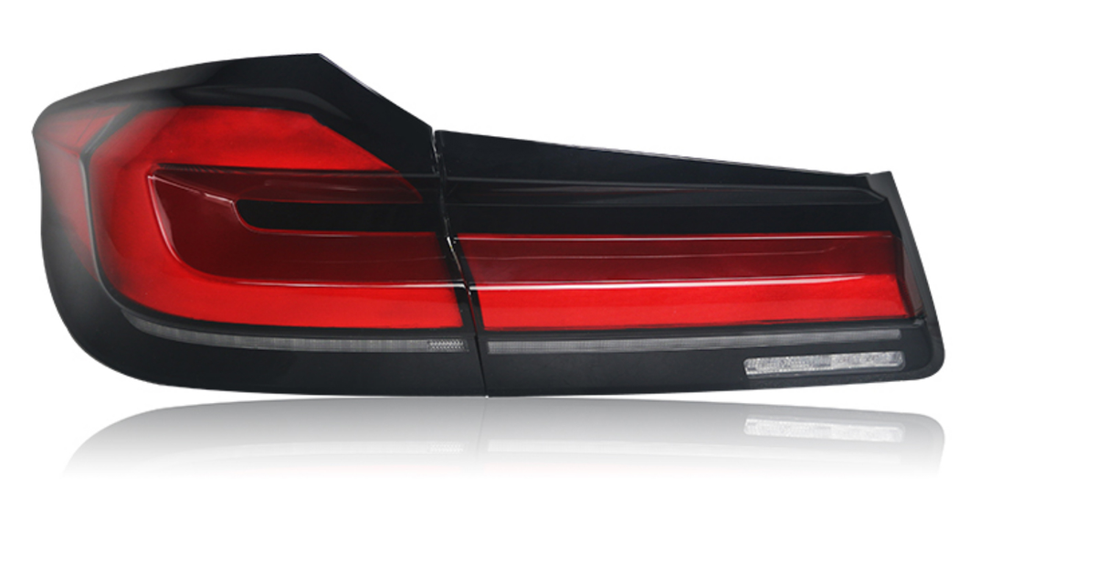 A sleek, red and black car taillight is shown reflecting light on a white surface, implying a modern automotive design.