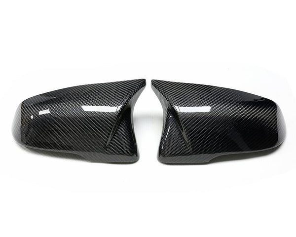 Two carbon fiber car wing mirror covers lie side by side, angled outward on a white background, showcasing a sleek, reflective design with a textured pattern.