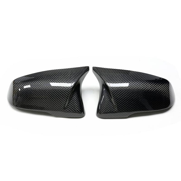 Two carbon fiber car wing mirror covers lie side by side, angled outward on a white background, showcasing a sleek, reflective design with a textured pattern.