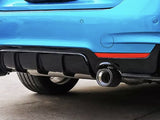 A blue car's rear features dual exhaust pipes and a black diffuser with red accents, parked on concrete.