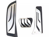 Three metallic vehicle pedal covers feature sleek black accents and grooves. They are designed for installation on an automobile's accelerator, brake, and clutch pedals, set against a plain white background.