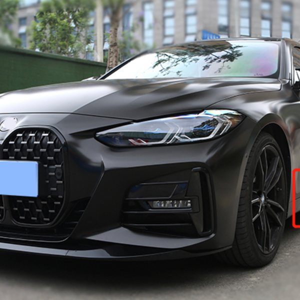 A sleek black car is parked on a city street. It has a large grille and modern headlights. A red rectangle highlights a detail near the car's bottom side.
