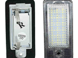 Two LED license plate lights; one shows the front with a grid of LED diodes under a clear cover, the other shows the back with a label marked 