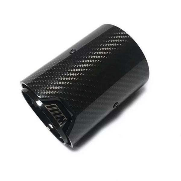 A glossy black carbon fiber exhaust tip lies against a white background, its cylindrical shape adorned with subtle diagonal patterns and screws, featuring an emblem resembling “M” outlined near the edge.