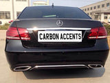 A black Mercedes-Benz car is parked on a concrete surface, displaying dual exhausts. The license plate reads 