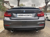 A gray BMW M235i, with dual exhausts, is parked on a residential street. The license plate reads 