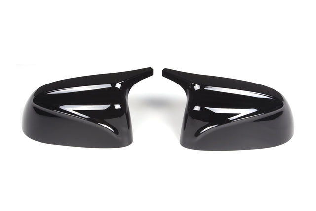 Two glossy black side mirror covers, angled symmetrically, with curved lines, placed on a plain white surface.