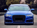 A blue car is parked on a road lined with trees. The car's grille displays the word 