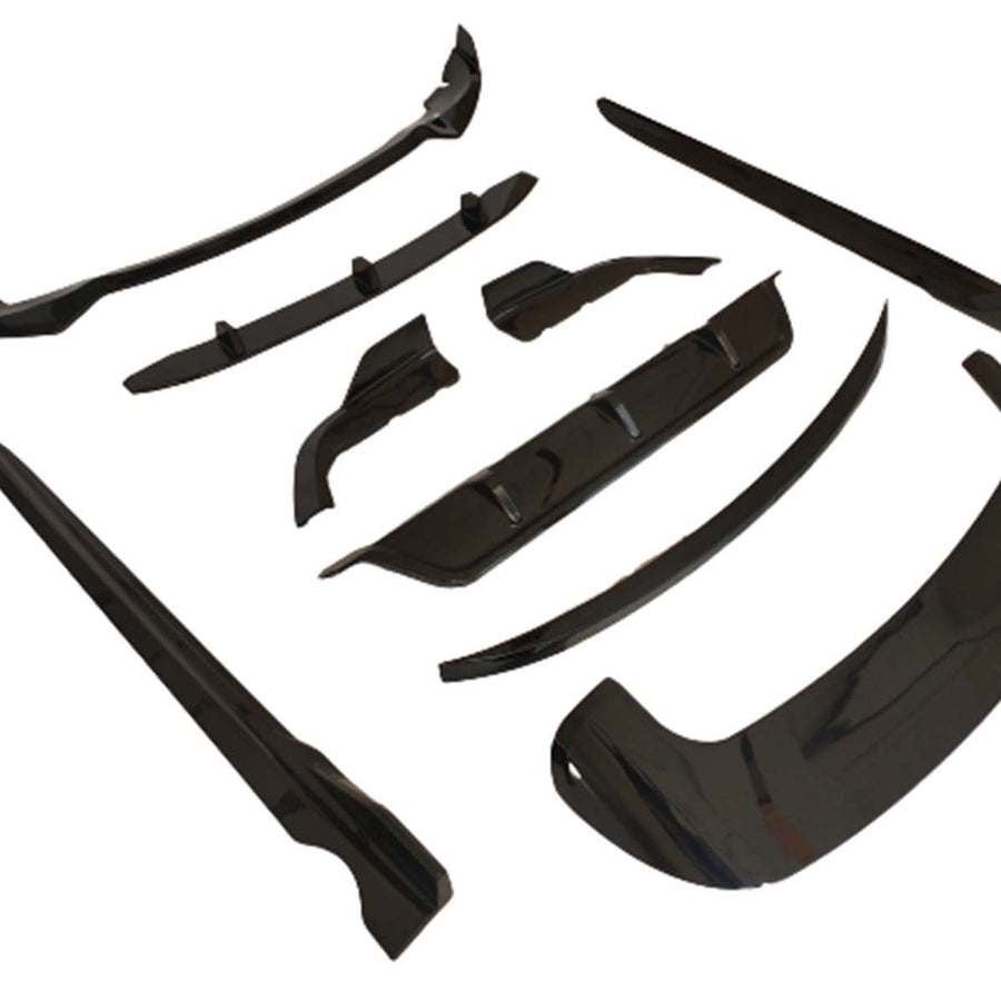 Black automobile body kit components are arranged on a white background. The kit includes various aerodynamic pieces like a front lip and side skirts, designed for vehicle exterior enhancements.